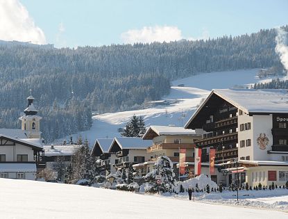 Verschneites Sporthotel Tirolerhof in Itter im Winter, rauch steigt aus dem Schornstein auf